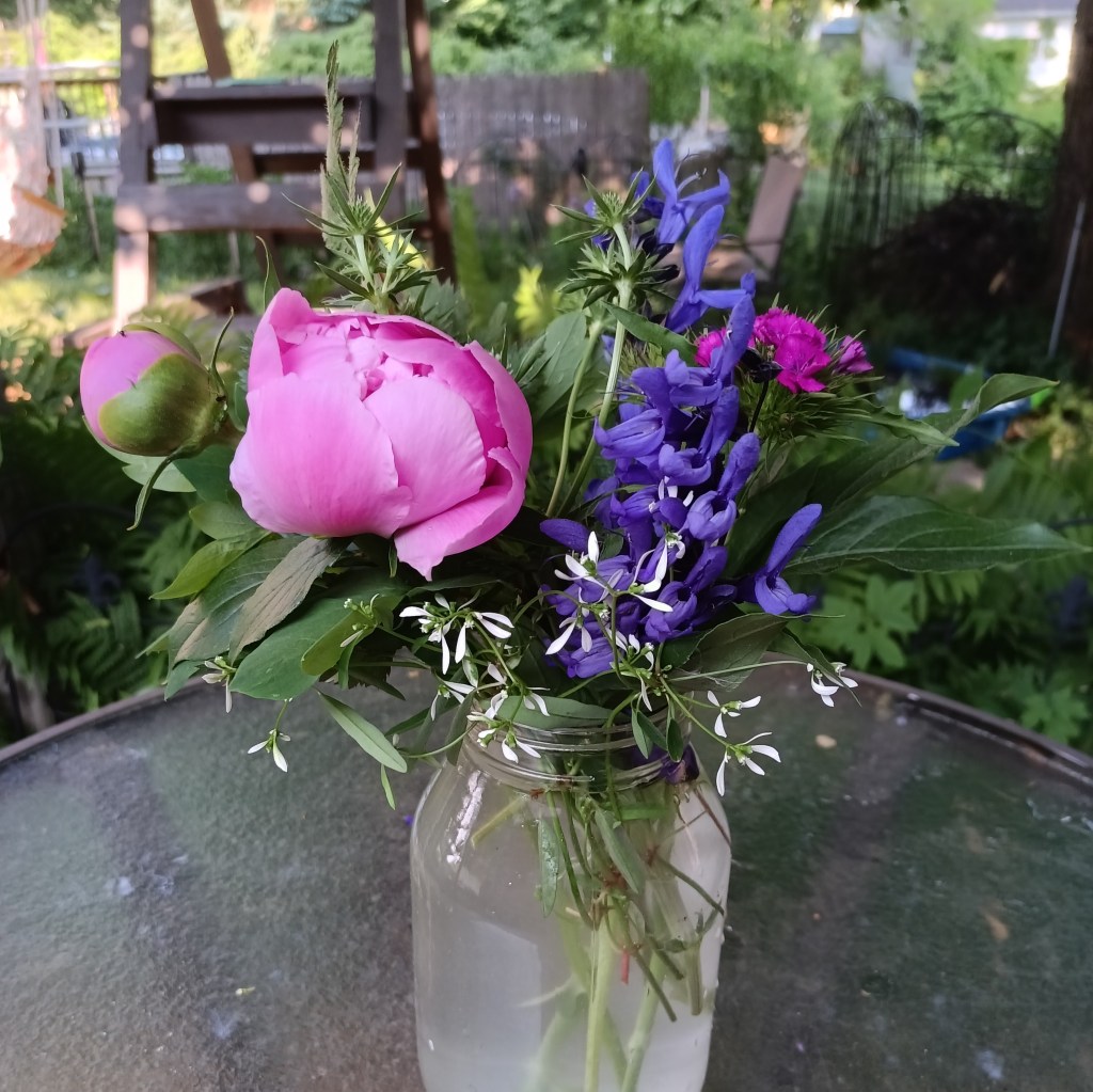 A bouquet of garden flowers in a mason jar on a patio table