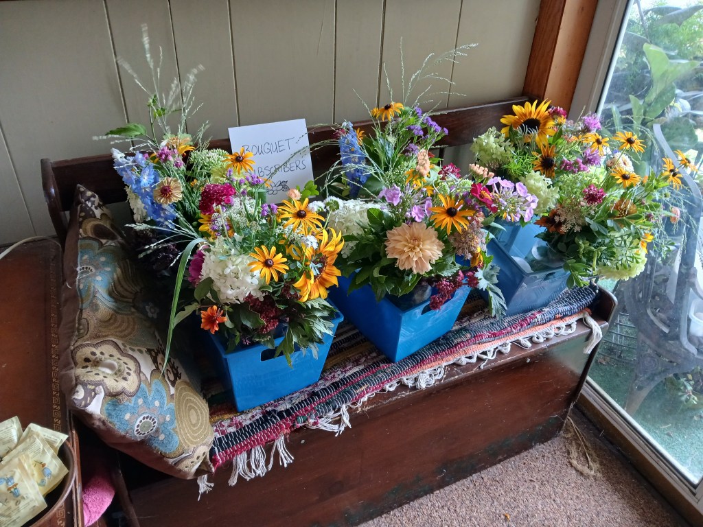 Bins of bouquets on a bench in a porch waiting to be picked up by subscribers